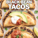 Crispy Sheet-Pan Black Bean Tacos baked golden brown with melted cheese, topped with avocado slices, salsa, and sour cream on parchment paper with lime wedges and cilantro.