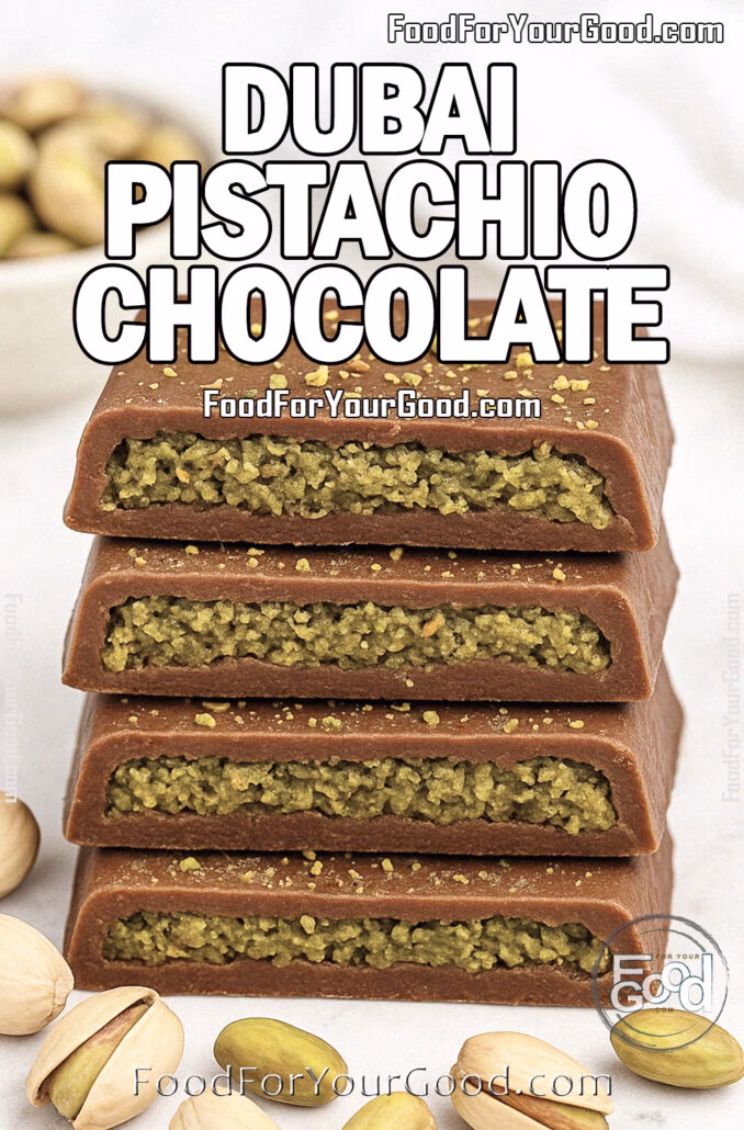 Dubai Pistachio Chocolate Rustic Dubai Pistachio Chocolate bars stacked on white marble, filled with textured pistachio cream and dusted with chopped pistachios, with whole pistachios scattered in front and a blurred bowl in the background.