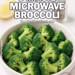 A white ceramic bowl filled with tender Easy 3-Minute Microwave Broccoli on a marble countertop with lemon wedge and olive oil in the background.