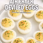 Easy Air Fryer Deviled Eggs served on a white ceramic plate, garnished with smoked paprika and fresh chives on a white marble countertop with a blurred towel and herbs in the background.