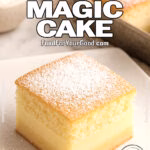 A slice of French Vanilla Magic Cake with airy sponge, creamy custard, and golden base, dusted with powdered sugar, served on a modern white square plate against a marble background.