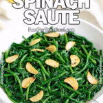 Garlic Lemon Spinach Sauté in a white bowl with garlic slices, fresh lemon, and garlic bulb in the background on white marble.