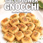 Golden Garlic Parmesan Cauliflower Gnocchi served on a white square plate with chopped basil and parmesan garnish, set on a marble countertop with cauliflower, ricotta, and cheese in the background.