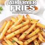 Golden Crisp Air Fryer Fries in a white bowl, garnished with parsley, on a marble countertop with potatoes and spices blurred in the background.