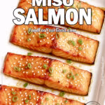 Golden Miso Salmon fillets roasted in a white baking tray lined with parchment paper, garnished with sesame seeds and green onions.