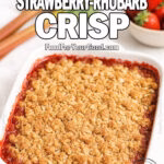 Golden Oat Strawberry-Rhubarb Crisp in a white dish with golden oat topping, fresh strawberries, and rhubarb on marble countertop.