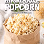 Homemade microwave popcorn served in a brown paper bag on a marble countertop with olive oil, paprika, and popcorn kernels in the background on FoodForYourGood.com
