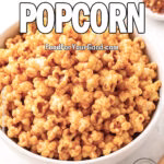 Hot Honey Popcorn in a white bowl on marble, with honey dipper, chili flakes, and honey jar in background.