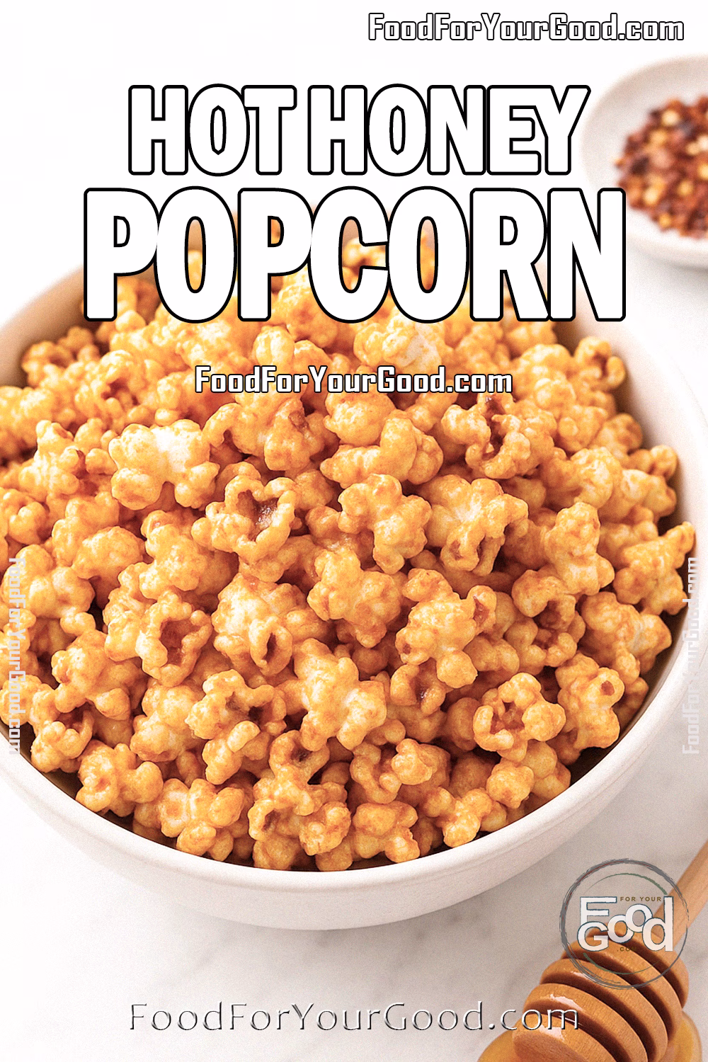 Hot Honey Popcorn Recipe | FoodForYourGood.com Hot Honey Popcorn in a white bowl on marble, with honey dipper, chili flakes, and honey jar in background.