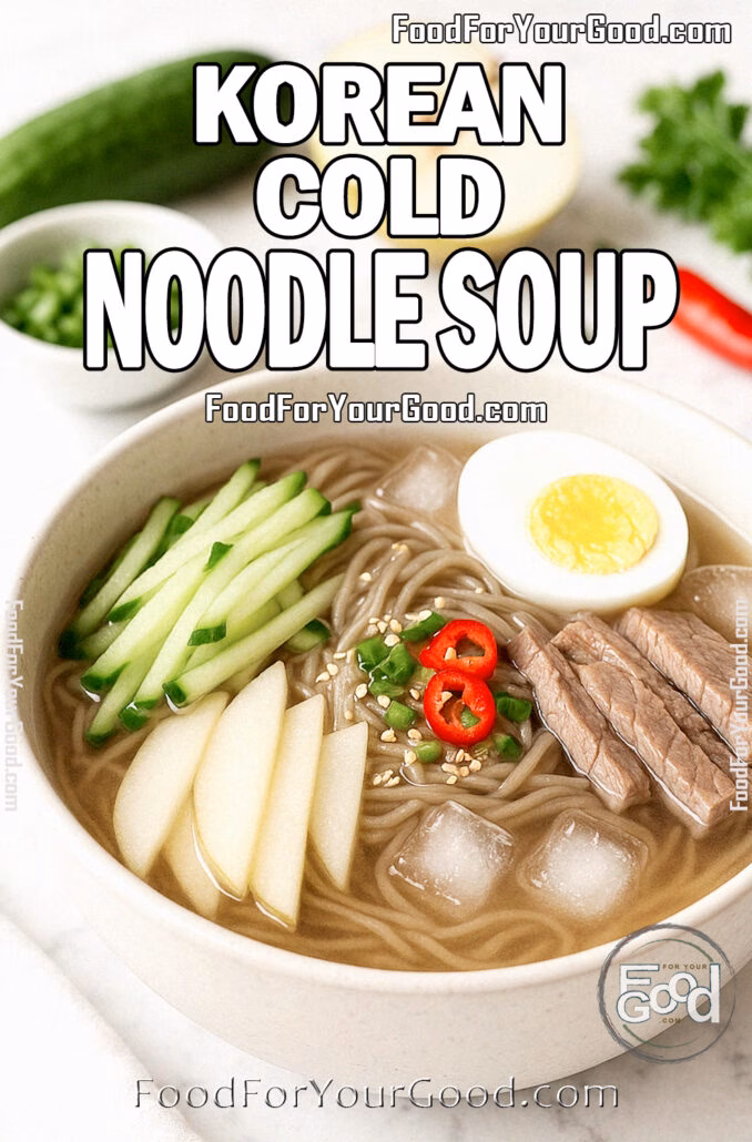 Korean Cold Noodle Soup Bowl of Korean Cold Noodle Soup with soba noodles, cucumber, pear, beef slices, boiled egg, and chili in icy broth on a marble surface.