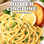 A bowl of Lemon Basil Butter Linguine with lemon slices, crispy bread, and fresh basil on marble.