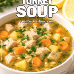 Bowl of Lemon Herb Turkey Soup on white marble countertop with carrots, potatoes, and orzo in a savory broth