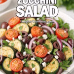 Mediterranean Zucchini Salad with roasted zucchini, cherry tomatoes, Kalamata olives, feta cheese, and herbs served in a white bowl on marble.