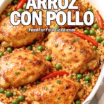 One-Pot Arroz con Pollo in a white dish on marble: golden, butter-glossed chicken thighs over yellow rice with peas, red pepper, cilantro, and lime wedges.