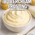 Royal Buttercream Frosting in a white bowl on a marble surface, with a spoonful of frosting in front and cupcakes in the background.
