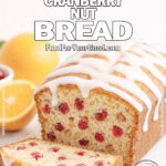 Rustic Orange Cranberry Nut Bread with powdered sugar glaze, sliced to show cranberries and walnuts on a white marble countertop.