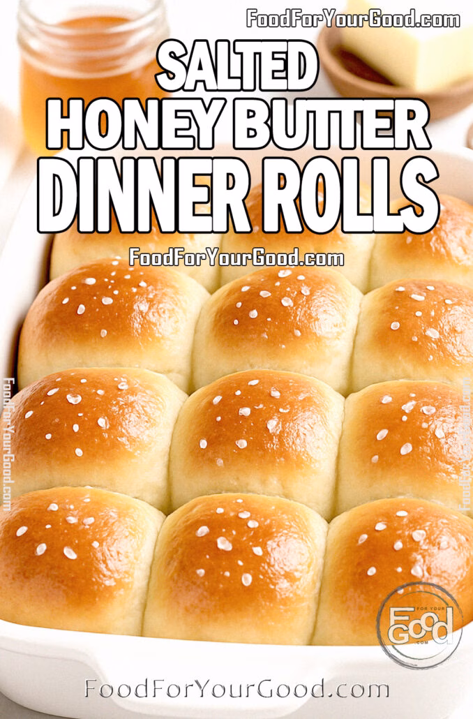 Salted Honey Butter Dinner Rolls in a white baking dish on marble with honey, butter, and flaky sea salt.