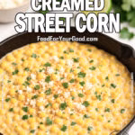 Skillet filled with creamy Mexican-style street corn topped with cotija cheese, cilantro, and chili powder on a marble countertop.