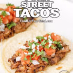 Pork street tacos with tomato salsa, chopped onion, cilantro, and queso fresco on corn tortillas.