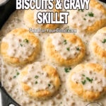 Southern Comfort Skillet Biscuits with golden biscuits drizzled in creamy sausage gravy inside a cast iron skillet, garnished with parsley, on a marble surface.