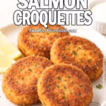 Four golden-brown Southern Salmon Croquettes on a white plate with lemon wedges and dipping sauce