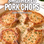 Southern Smothered Pork Chops in creamy onion gravy, garnished with fresh parsley, served in a white skillet on marble background for FoodForYourGood.com