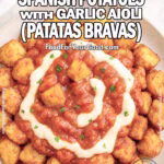 Spicy Spanish Potatoes with Garlic Aioli (Patatas Bravas) served in a white ceramic dish on marble with parsley garnish.