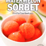 A white ceramic bowl filled with vibrant watermelon sorbet scoops drizzled with honey, garnished with a fresh watermelon wedge, placed on a white marble surface with honey and mint in the blurred background.