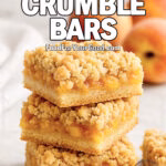 Sweet Peach Crumble Bars on white marble with fresh peaches in the background, stacked to show buttery crust, juicy peach filling, and golden crumb topping.