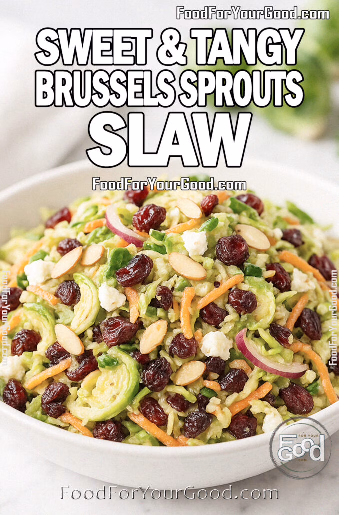 Sweet & Tangy Brussels Sprouts Slaw in a white ceramic bowl, topped with almonds, cranberries, and feta. Styled on a marble surface with fresh Brussels sprouts and a white towel in the background.
