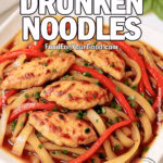 Thai Chicken Drunken Noodles on a white square plate—wide, wavy rice noodles with seared chicken, red bell pepper, and chopped basil on white marble.