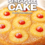 Tropical Pineapple Cake with powdered sugar, baked pineapple rings, and cherries on a white plate over white marble, with a towel in the background for FoodForYourGood.com