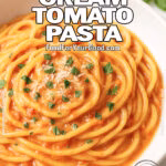 Tuscan Cream Tomato Pasta served in a white plate on marble background with basil garnish.