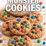 Ultimate Monster Cookies on white marble with colorful candy-coated chocolates and scattered cookie crumbs in the background.