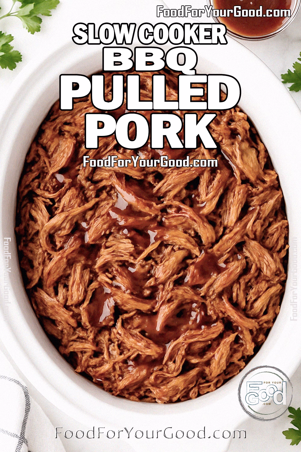 Slow Cooker BBQ Pulled Pork Recipe on FoodForYourGood.com Slow Cooker BBQ Pulled Pork in a white slow cooker, tender shredded meat drizzled with barbecue sauce, styled on a marble countertop with fresh parsley, garlic, and a white towel.